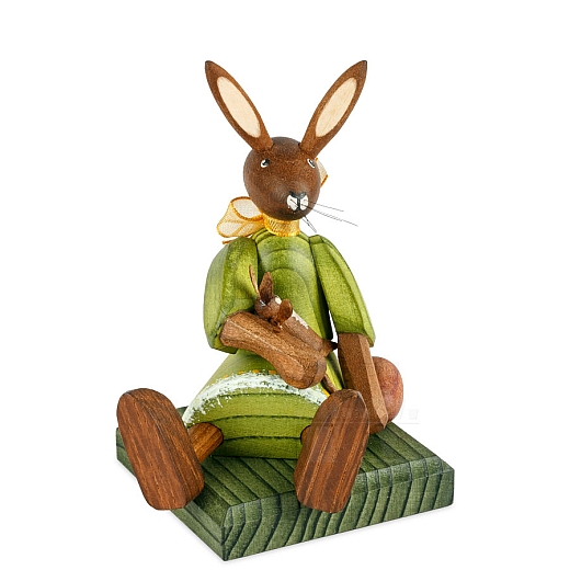 Easter bunny girl sitting with green dress and doll